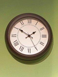 Big old clock with Roman numbers at green wall