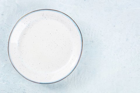An empty white plate with a blue rim, overhead flat lay shot on a slate background, with copy