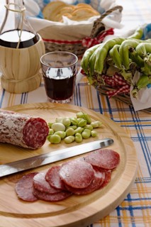 Meat chopping board of traditional Italian salami with broad bean and red wine