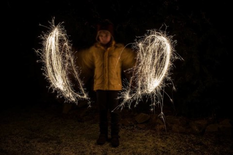 A child paints circles of light with sparklers