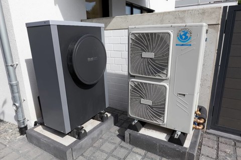 Outdoor units of an air-to-water heat pump in front of a newly built two-family house, heating and