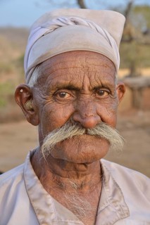 Herdsman from the tribe of the Maldhari in a typical white robe and golden earrings, portrait, Gir