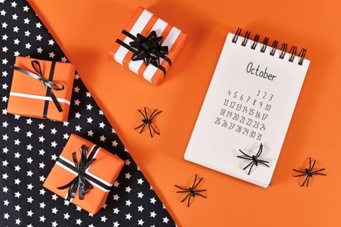 Calendar sheet for month October with Halloween spiders and gift boxes on orange and black