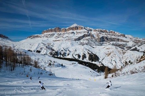 View of a ski resort piste with people skiing in Dolomites in Italy. Ski area Arabba. Arabba,