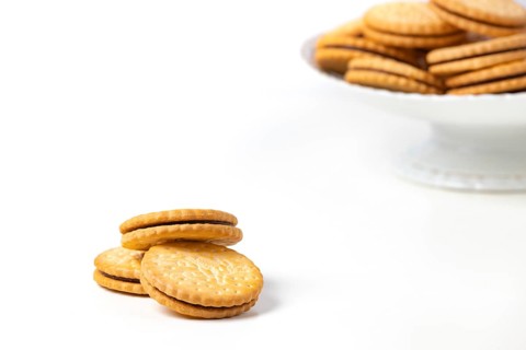 Double biscuits in and next to white bowl, white background, copy space