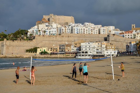 Beach volleyball players on the beach of Peñíscola, in the background the old town, province
