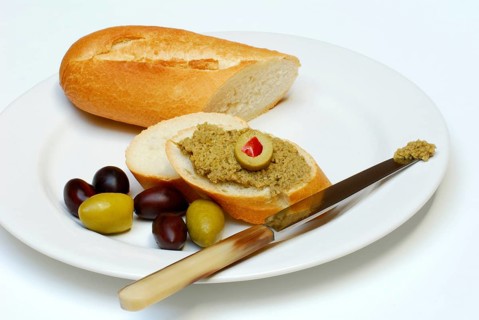 Tapenade on baguette, olives, olive paste, plate, knife, bread