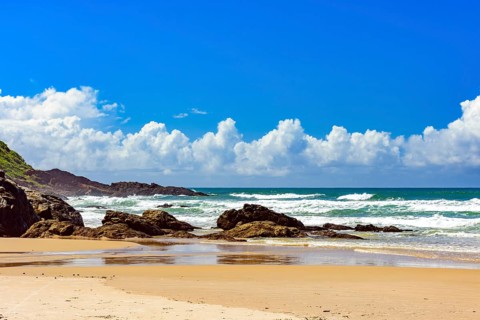 Beach with waves breaking against the rocks on a sunny day in the town of Serra Grande on the coast