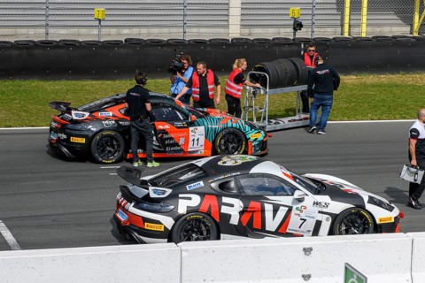 Team manager of car racing team and mechanic with spare tyres next to racing car Sports car Porsche