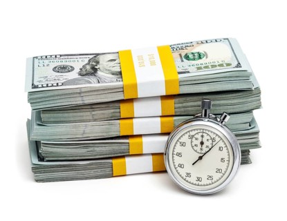 Time is money concept, stopwatch and stack of new 100 US dollars 2013 edition banknotes bills