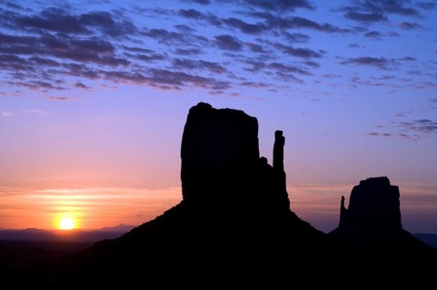 Eroded sandstone rock formations, buttes the Mittens silhouette at dawn in Monument Valley Navajo