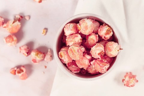 Top view of pink colored strawberry flavored sweet popcorn in white bowl