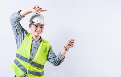 Portrait of smiling engineer pointing aside isolated. Handsome engineer pointing an advertisement