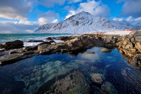 Beach of Norwegian sea on rocky coast in fjord on sunset in winter. Vareid beach, Lofoten islands,