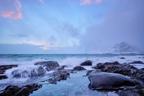 Beach of Norwegian sea on rocky coast in fjord on sunset in winter. Vareid beach, Lofoten islands,