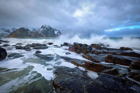 Waves crushing on rocks on rocky coast of fjord of Norwegian sea in winter. Lofoten islands,