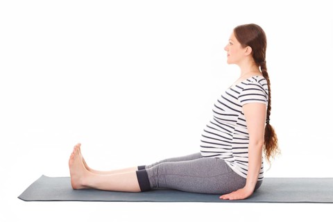 Pregnancy yoga exercise, pregnant woman doing yoga asana Dandasana Staff pose isolated on white