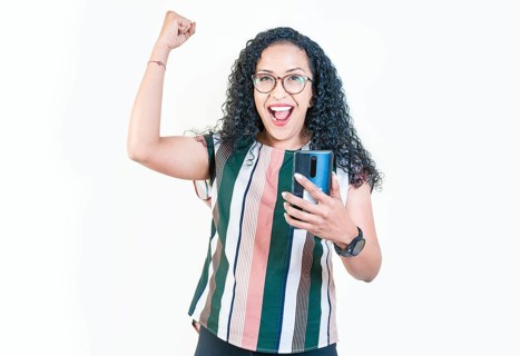 Winner young afro girl holding phone excited isolated. Happy afro woman holding smartphone and