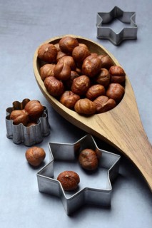 Wooden ladle with hazelnuts, cookie cutters, baking ingredient