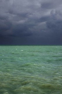 Dark rain clouds over emerald coloured sea water