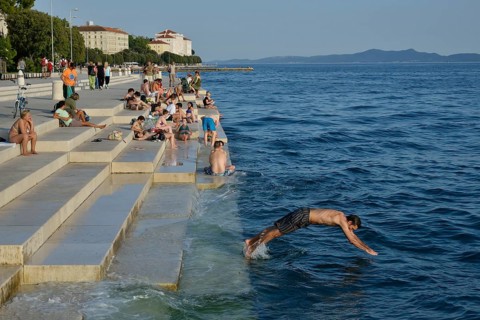 Visitors basking in the evening sun at the Sea Organ by architect Nikola Bašic, Zadar, Dalmatia,