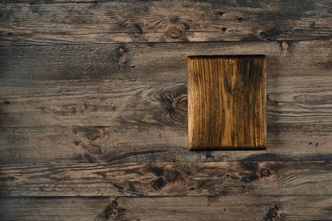 A handcrafted wooden cutting board rests on a rustic wooden table, showcasing the grain\'s beauty