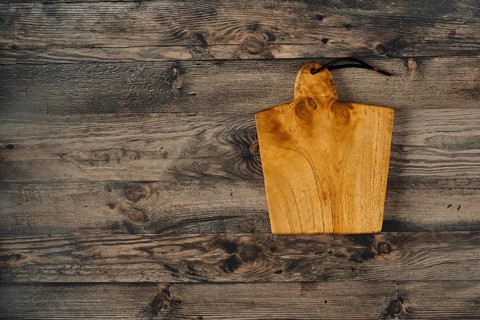 A beautifully crafted wooden cutting board rests on a rustic wooden countertop, showcasing its