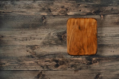 A beautifully crafted wooden cutting board is placed on a rustic wooden table, showcasing its