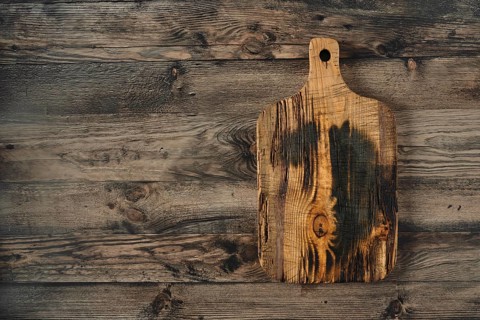 A beautifully crafted wooden cutting board is placed on a weathered wooden surface, showcasing its