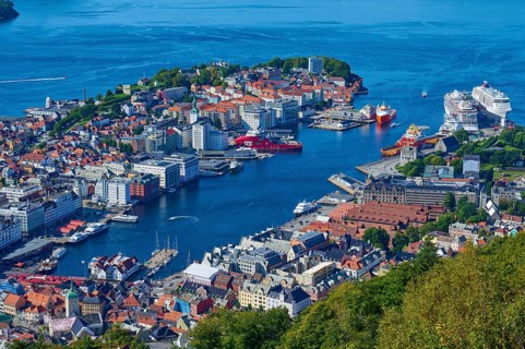 Picturesque harbour of Bergen with buildings, boats and houses, surrounded by water and green