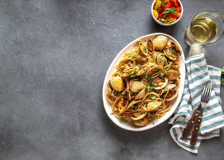 Seafood Pasta. ITALIAN SPAGHETTI ALLE VONGOLE. Clams spaghetti on white plate with white wine, gray
