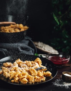 Kaiserschmarrn on a black plate, sprinkled with sugar, dark background
