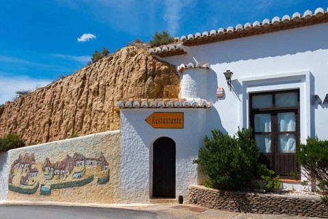 Small restaurant in a white building with painted walls and rustic charm under a blue sky, Pedro