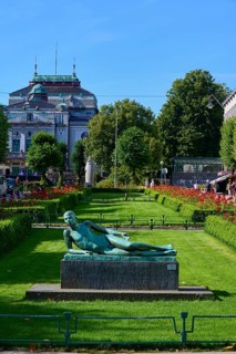 Lying poet statue in front of a historic building and sunny weather, Bergen, Vestland, Norway,