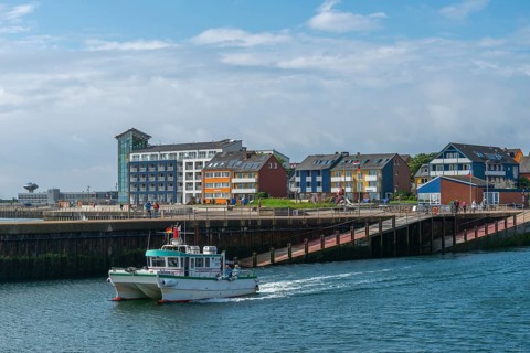 View of the Helgpländer Unterland on the north-east harbour with departing boat of the island tour,