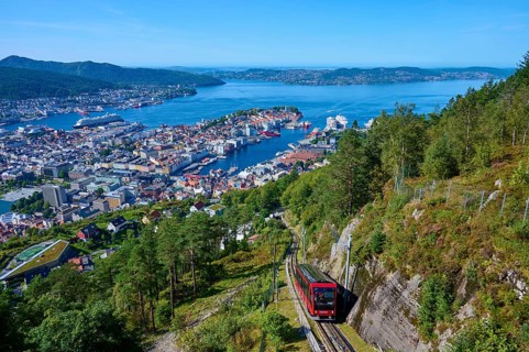 Panoramic view of Bergen with harbour on a clear day, cable car ascending the wooded mountain,