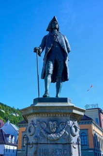 Ludvig Holberg statue on a pedestal in front of historic buildings on a sunny day, Bergen,