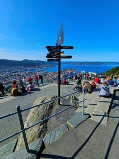 View of the city of Bergen with fjord, Bergen, signposts and a crowd of people admiring the