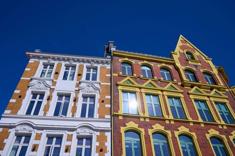 A historic building with an elaborate façade and many windows, surrounded by a clear blue sky,