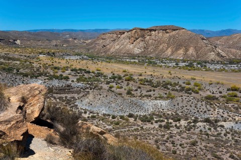 Extensive desert landscape with mountains and dry vegetation under a bright blue sky, Llano de