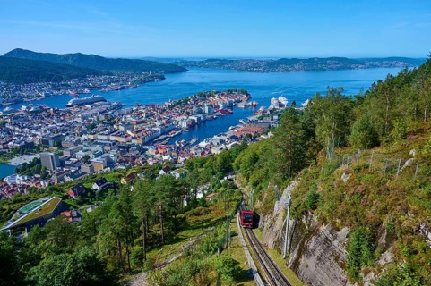 Panoramic view of Bergen with harbour on a clear day, cable car ascending the wooded mountain,