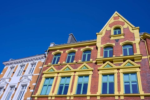 A historic building with an elaborate façade and many windows, surrounded by a clear blue sky,