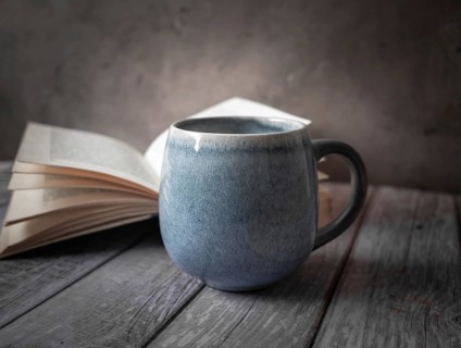 A large cup in front of an open book strjend