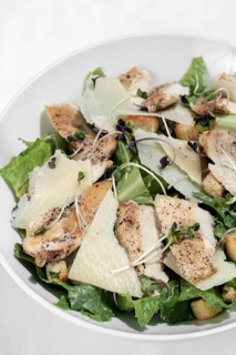 Organic chicken caesar salad with parmesan cheese and croutons on white table background