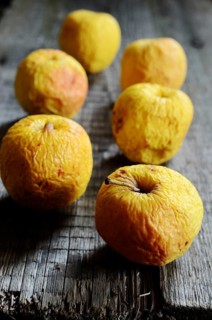 Wrinkled yellow apples on a wooden board