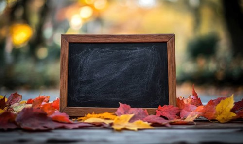 Empty chalkboard framed in wood surrounded by vibrant autumn leaves in an outdoor setting with a