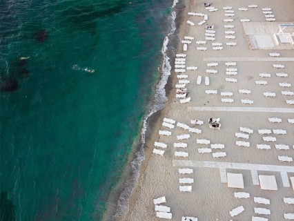 Beach and sunbeds by the sea with emerald water. Summer vacation by the sea