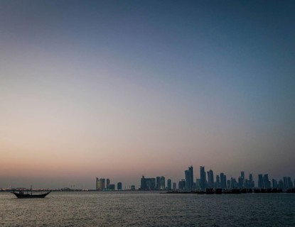 Doha city skyscrapers urban skyline view and dhow boat in qatar at sunset