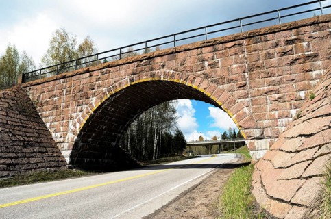 Stone viaduct over the road in summer