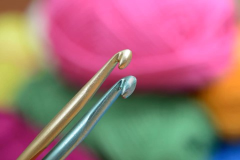 Two crochet hooks on a background of colorful wool